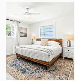 Primary bedroom with layered bedding and warm wood headboard