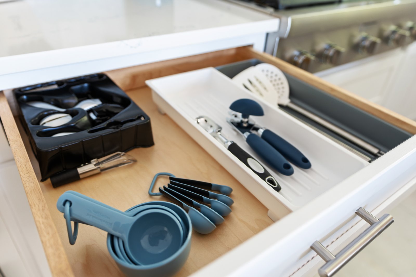 Kitchen drawer with organizer inserts holding measuring cups, utensils, and tools