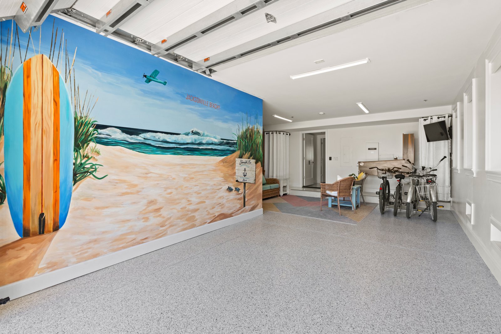 Garage finished with a floor-to-ceiling beach mural, bikes, and seating
