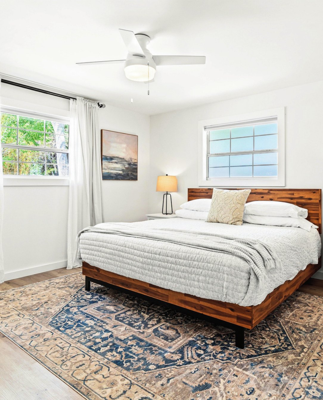 Primary bedroom with layered bedding and warm wood headboard